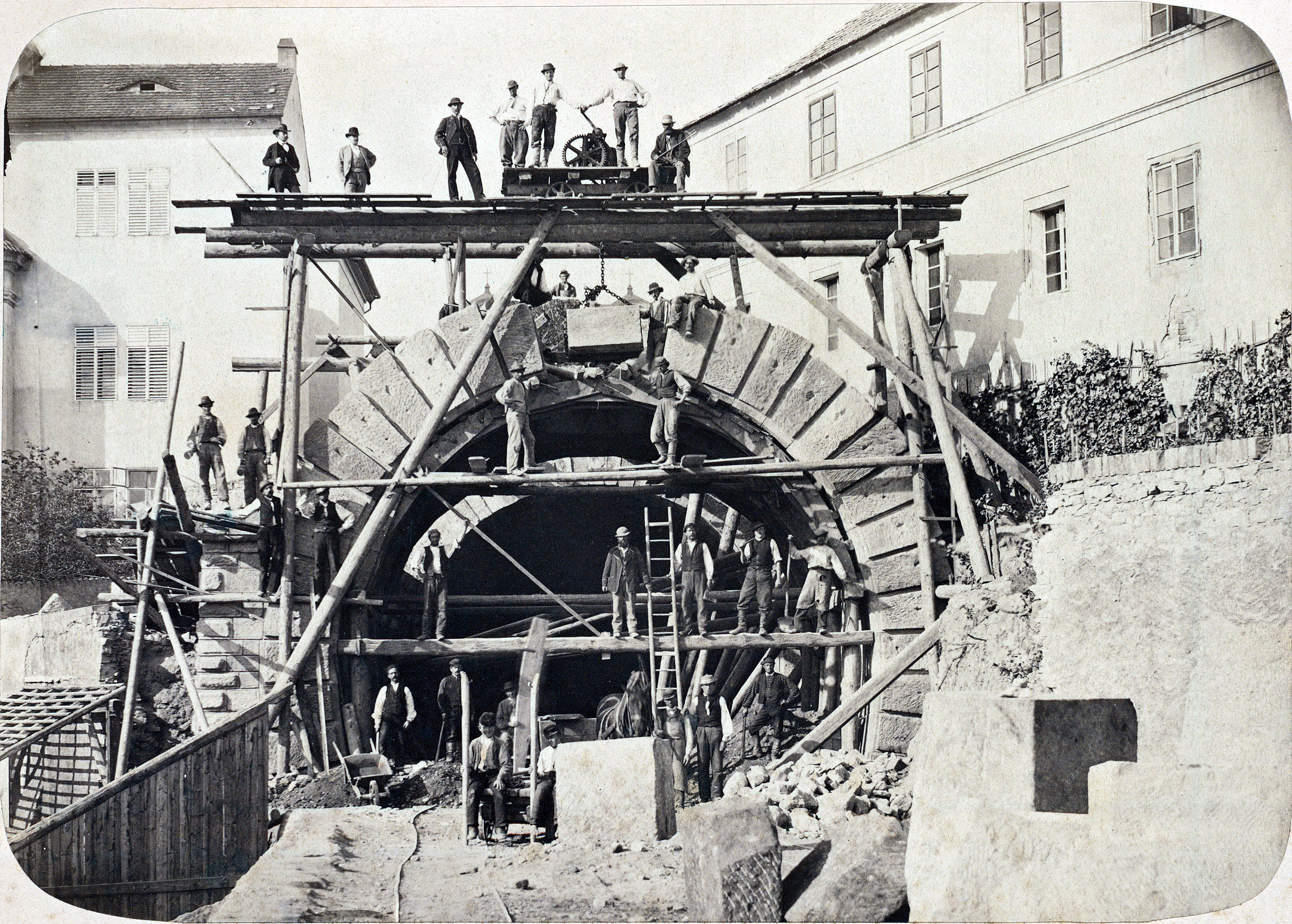 Historical photograph of a team building a stone arch on scaffolding